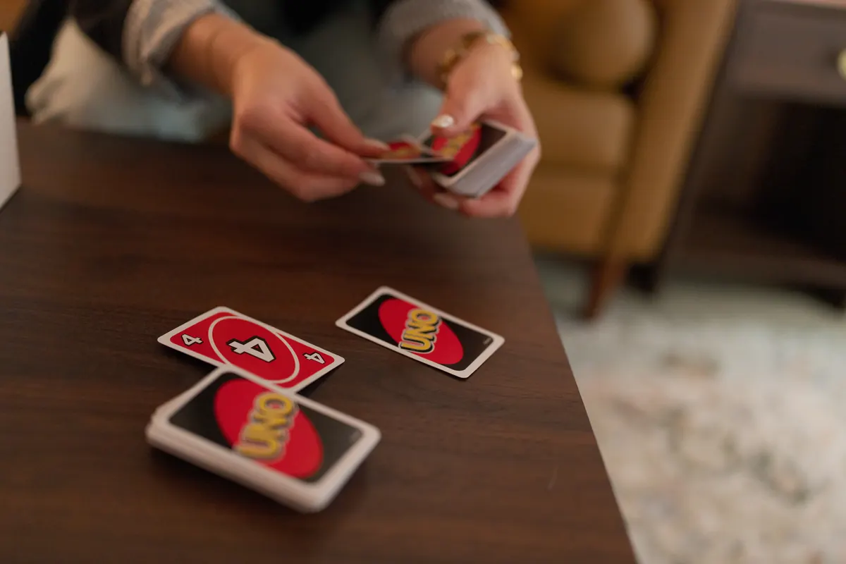 Two hands dealing a card game across a wooden table